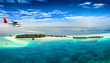 Wasserflugzeug fliegt über Malediven Insel mit türkisem Wasser und feinem Sandstrand