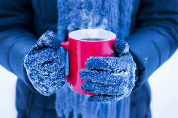 woman holding red cup with hot drink in winter