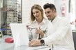© FotoAndalucia - Couple in optician glasses store trying on models with mirror