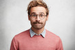 © WHstudio Leushin N - Clumsy male geek presses lips, looks in bewilderment, feels embarrassed in presence of beautiful woman, wears round big spectacles, isolated over white concrete background. Excited emotional male