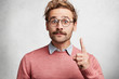© WHstudio Leushin N - Handsome bearded man has trendy hairdo and mustache raises fore finger as gets good idea, has intriguing and clever expression, expresses his confidence, isolated over white concrete background