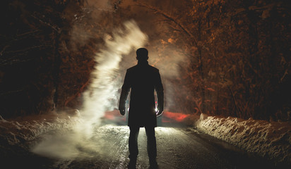 The man stand near the smoke on the snowy road. evening night time