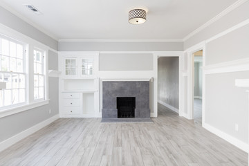 Living Room interior after remodelling with fire place and grey wooden floor.