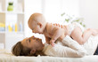 © Oksana Kuzmina - Happy mom playing with her kid in bed enjoying sunny morning in home bedroom