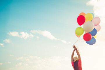 Girl hand holding multicolor balloons done with a retro instagram filter effect, concept of happy birth day in summer and wedding honeymoon party, Vintage color tone style