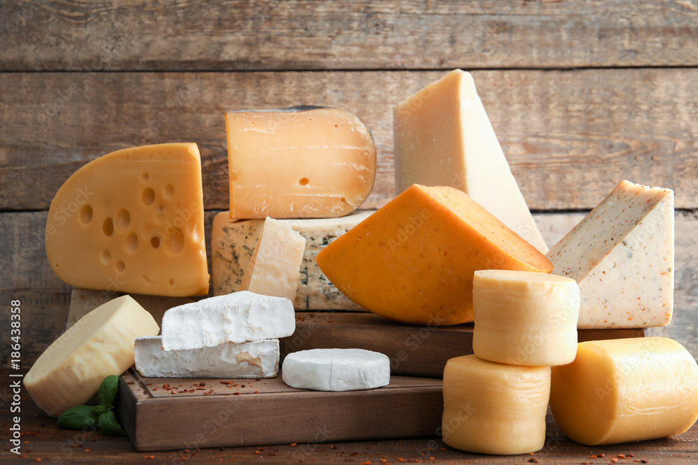 Wooden board with different kinds of delicious cheese on table