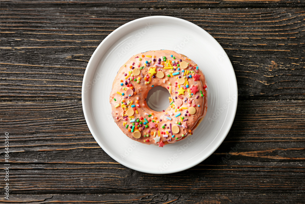Plate with tasty donut on wooden table