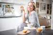© SVP Productions - Beautiful blond  caucasian woman posing in her kitchen, while drinking coffee or tea and eating a healthy breakfast meal full of cereal and other healthy foods, including fruit