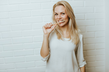 Wall Mural - Beautiful blond  caucasian woman posing in front of a white brick backround and  having fun