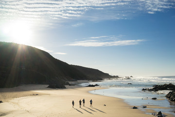 A small group of runners exploring the beach and coastline of the Garden Route of South Africa