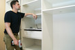 © Vitalii Vodolazskyi - Repair man looking at cupboard or wardrobe. Installation of furniture.