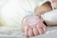 Close Up Of Baby Hands With Pacifier. Focus Is On Baby Hands