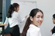 © tuaindeed - Cheerful young Asian business woman smiling between presentation in office.