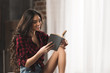 © LIGHTFIELD STUDIOS - smiling girl in checkered shirt and denim shorts reading book at home