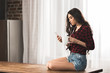 © LIGHTFIELD STUDIOS - sexy young woman in earphones using smartphone while drinking coffee at home