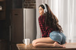 © LIGHTFIELD STUDIOS - surprised girl in denim shorts and headphones looking away while sitting on table with cup of coffee