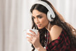 © LIGHTFIELD STUDIOS - attractive young woman listening music in headphones and drinking coffee at home