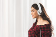 © LIGHTFIELD STUDIOS - side view of smiling girl in checkered shirt listening music in headphones and looking away