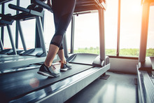 Close Up Of People Who Exercising On Treadmill. Close-up Of Woman Legs Walking By Treadmill In Sports Club. Fitness And Body Build Up Concept. Workout And Strength Training Concept. Sport Club Theme.