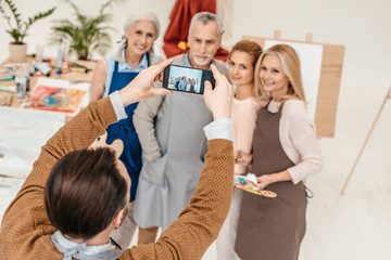 Canvas Print - man with smartphone photographing senior students at art class