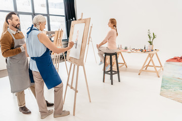 Canvas Print - senior artists painting portrait on easels at art class