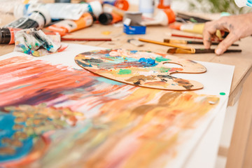 Wall Mural - cropped shot of human hand and palette with paints on table