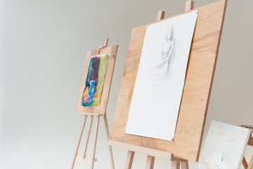 Wall Mural - easels with artistic paintings in empty art studio on grey