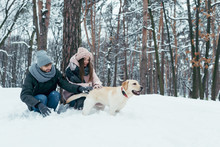Young Couple Having Fun Together With Dog In Winter Park