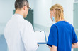 © LIGHTFIELD STUDIOS - back view of doctor in white coat and female surgeon discussing diagnosis in hospital