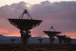 © Cavan Images - Satellite dishes on field against cloudy sky during sunset