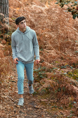 Wall Mural - Teenage boy walking though a woodland in autumn