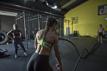 Wall Mural - Young woman training rope in health club with rope