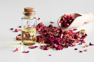 Wall Mural - A bottle of rose essential oil with dried rose petals