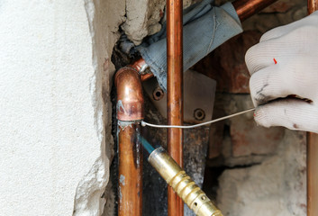 Wall Mural - A worker is  soldering copper pipes.