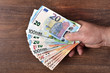 A man holds a euro banknote in his hand. In the hand of money. A man received a salary.