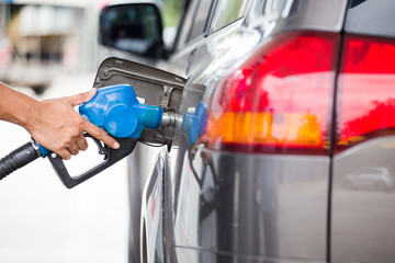Hand refilling the car with fuel at the refuel station.