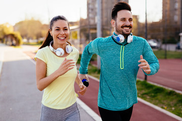 Wall Mural - Young attractive couple running outside on sunny day