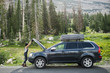 © Jessica Peterson/Tetra Images - Side view of woman opening a car hood in the forest