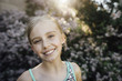 © Cavan Images - Portrait of smiling girl standing against plants at backyard