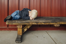 Full Length Of Boy Sleeping On Wooden Bench