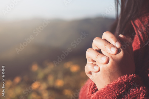 Fotografía Woman hands folded in prayer in beautiful nature background with sunlight in vin