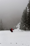 Fototapeta Tulipany - A tourist is walking through the winter foggy forest in Carpathian mountains