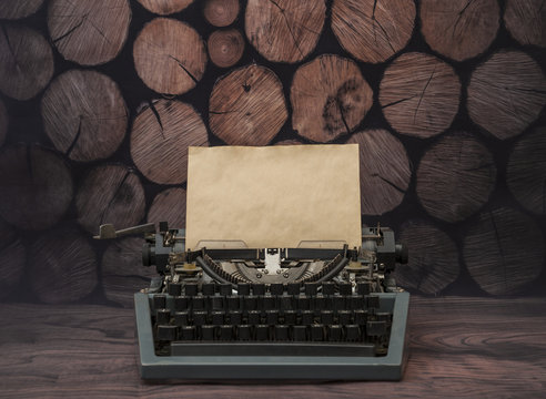 Vintage typewriter with a clean yellowed old sheet of paper. on a background of a tree of rustic logs. for the design of your text design