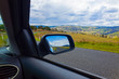Romantic country road reflected in car mirror in rural mountains