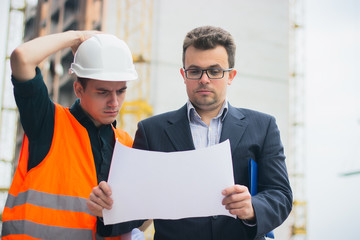 Young business man at construction business plans to make their work more efficient.. Warm orange light.