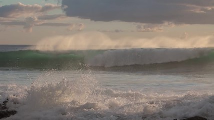 Wall Mural - shorebreak ocean waves near rocky coast and cliffs, rough sea water at sunset time