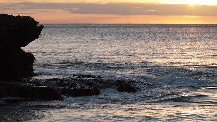 Wall Mural - shorebreak ocean waves near rocky coast and cliffs, rough sea water at sunset time