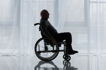 Wall Mural - Senior thoughtful man in wheelchair in front of window