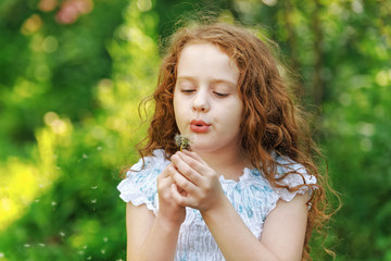 Wall Mural - curly girl blowing dandelion