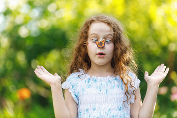 Wall Mural - Surprised girl with a butterfly on her nose, focus on a girl face.